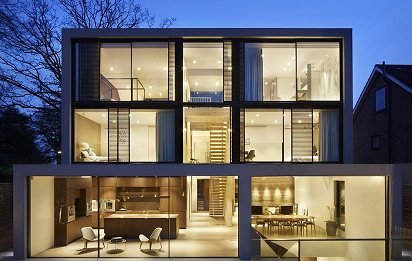 Modernes Wohnhaus in der Dämmerung mit raumhohen, beleuchteten Fensterfronten