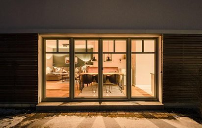 Beleuchtete Terrassenfront mit großer Hebe-Schiebetür bei Nacht